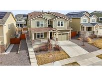 Charming two-story home with green siding, a covered porch, well-maintained landscaping, and an attached garage at 14881 Chicago St, Parker, CO 80134