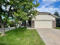 Charming home featuring a well-manicured lawn, mature tree, and a two-car garage, creating a welcoming curb appeal at 20532 E Lake Cir, Centennial, CO 80016