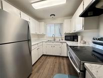 Well-lit kitchen with stainless steel refrigerator, oven, dark countertops, and white cabinets at 8625 Clay St # 228, Westminster, CO 80031