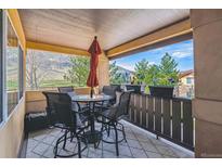 Covered patio with an umbrella-shaded table, four chairs, and decorative flower boxes showing neighborhood views at 9836 W Freiburg Dr # 4E, Littleton, CO 80127