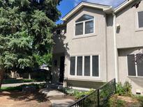 Charming two-story townhome featuring stucco exterior, large windows, and mature landscaping in a desirable neighborhood at 490 Jackson St, Denver, CO 80206