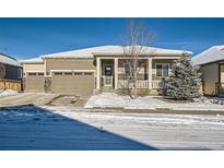 Ranch style home with two-car garage, covered porch, and snowy landscaping at 7071 Greenwater Cir, Castle Rock, CO 80108