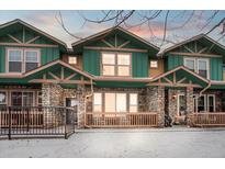 Inviting townhomes featuring green siding, stone accents, and charming front porches in a snow-covered setting at 643 S Norfolk Way, Aurora, CO 80017