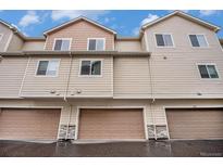 Exterior view of tan townhomes with attached garages featuring stone accents and neutral trim at 11250 Florence St # 29D, Commerce City, CO 80640