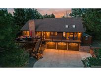 Beautiful brown two-story home featuring large deck, outdoor seating and three-car garage with well-lit driveway at 8140 Lightening View Dr, Parker, CO 80134