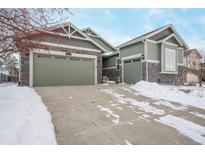 Green two-story house with attached garage and snowy driveway at 26674 E Phillips Pl, Aurora, CO 80016