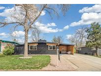 Charming single-story home featuring a black brick exterior, well-kept lawn, and covered seating area at 6170 Estes Ct, Arvada, CO 80004
