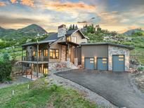 Striking exterior of home with stone accents, a three-car garage, and mountain views at 12947 Lazy Dog Ln, Littleton, CO 80127