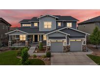Beautiful two-story home with a manicured lawn, stone accents, and a three-car garage under a colorful dusk sky at 22263 Boundstone St, Parker, CO 80138