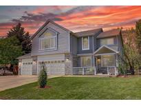 Charming two-story home with a three-car garage, well-manicured lawn, and inviting front porch at sunset at 20113 Edinborough Ct, Parker, CO 80138