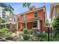 Charming two-story brick home with a landscaped front yard and inviting porch swing at 1007 N Ogden St, Denver, CO 80218