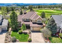 Beautiful two-story home with stone accents, manicured lawn, mature trees and mountain view at 7083 Turweston Ln, Castle Pines, CO 80108