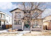 Inviting two-story home boasting stone accents, a dark roof, a welcoming green entry door and an attractive front yard at 2540 S Monroe St, Denver, CO 80210