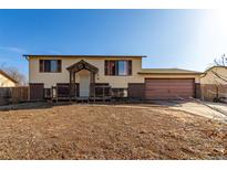 Split-level home features light yellow paint, brick accents, and a spacious two-car garage at 15492 E Floyd Ave, Aurora, CO 80013