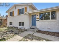 Charming two-story home with white brick, wood shutters, a blue door, and a well-maintained front yard at 709 S Alkire St, Lakewood, CO 80228