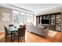 Bright living room with hardwood floors, large windows, a dining area, and custom built-in shelving at 7600 Landmark Way # 904, Greenwood Village, CO 80111