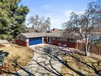 Charming single-story home with a brick facade, blue garage door, and well-maintained lawn and patio at 2300 Willow Ln, Lakewood, CO 80215