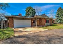 Brick home featuring a two-car garage and manicured landscaping at 1705 Stonehenge Dr, Lafayette, CO 80026