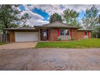 Charming brick single-story home with a two-car garage, red shutters and well-maintained front lawn at 1705 Stonehenge Dr, Lafayette, CO 80026