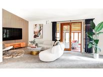 Bright living room featuring a stylish white sofa, modern decor, and a sliding glass door to the backyard at 6842 W Eldorado Pl, Lakewood, CO 80227
