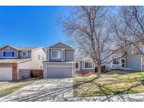 Inviting two-story home with a well-manicured front lawn, a gray siding and an attached garage at 9851 Castle Ridge Cir, Highlands Ranch, CO 80129