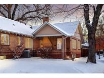 Charming brick home with snow-covered roof and winter trees showcasing classic curb appeal at 1817 E Center Ave, Denver, CO 80209