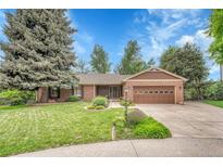 Charming brick home featuring a well-manicured lawn, beautiful landscaping, and a two-car garage at 5964 S Florence Ct, Englewood, CO 80111