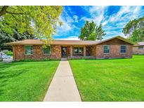 Charming one-story brick home featuring a well-manicured lawn and a concrete walkway to the front door at 2311 Emery Pl, Longmont, CO 80501