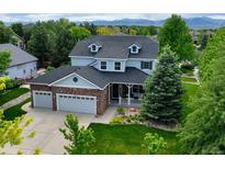 Beautiful two-story home with a stone accent garage, manicured lawn, and mature trees at 14675 Golden Eagle Run, Broomfield, CO 80023