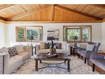Inviting living room featuring a vaulted wood ceiling, bay windows, and comfortable seating arrangements at 21345 Cliffwoods Trl, Morrison, CO 80465