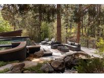 Beautiful backyard setting, featuring a pool, water feature and outdoor seating area amidst mature trees at 1070 Cypress Way, Castle Rock, CO 80108