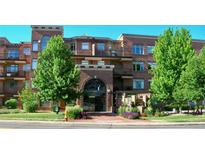 Brick apartment building with archway entrance, lush landscaping, balconies, and visible address at 2700 E Cherry Creek S Dr # 302, Denver, CO 80209