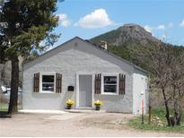 Charming stucco home featuring a quaint front yard with a mountain backdrop and lovely curb appeal at 9180 Spruce Mountain Rd, Larkspur, CO 80118