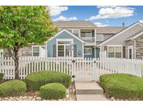 Charming townhome featuring a white picket fence, lush landscaping, and a welcoming entryway at 11386 Grove St # B, Westminster, CO 80031