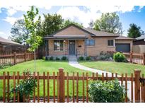 Charming brick home featuring a well-manicured lawn and a classic wooden picket fence at 2415 Pontiac St, Denver, CO 80207