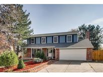 Charming two-story home with blue siding, brick accents, a well-manicured lawn, and a spacious two car garage at 9926 W Nova Pl, Littleton, CO 80127