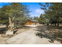 Charming ranch-style home with mature trees, long driveway, and a striking eagle statue at the entrance at 10963 N Chatfield Dr, Littleton, CO 80125