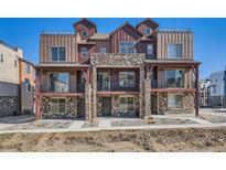 New construction townhomes featuring stone accents, balconies, and rooftop terraces at 9660 Browns Peak Cir, Littleton, CO 80125