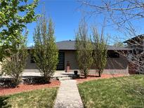 Charming brick home with a modern front door, green grass, and attractive landscaping at 380 S Jersey St, Denver, CO 80224