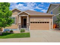 Charming tan-colored home with a two-car garage, a covered entry, and a well-manicured lawn at 1462 Raindrop Way, Castle Rock, CO 80109