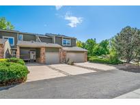 Two-story townhome featuring attached garages, brick accents, covered entry and well maintained landscaping at 4825 S Ammons St # 102, Littleton, CO 80123