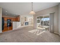 Open-concept living area with sliding glass doors to the deck, and view into the kitchen and fireplace at 74 Whitehaven Cir, Highlands Ranch, CO 80129