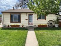Charming single-story home featuring a well-manicured lawn and inviting curb appeal with flower boxes and a decorative wagon wheel at 4825 Estes St, Arvada, CO 80002