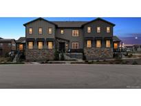 Stylish townhome featuring a stone facade, dark gray siding, and well-maintained landscaping at 9836 Mount Kataka Pt, Littleton, CO 80125