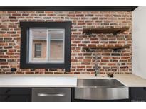 Modern kitchen features a stainless steel sink, exposed brick, and floating shelves at 3731 N Race St, Denver, CO 80205
