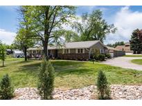 Charming single-story home boasts a well-manicured lawn, mature trees, and inviting front porch at 10220 W Montgomery Ave, Littleton, CO 80127