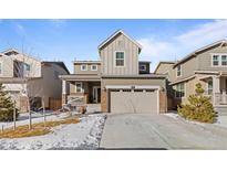 Two-story house with gray siding, two-car garage, and snowy front yard at 697 N Bersshine Ct, Watkins, CO 80137