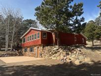 Charming red home featuring stone accents and large windows to enjoy the natural views at 11599 Ranch Elsie Rd, Golden, CO 80403