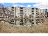 A condominium exterior is reflected in the calm waters of a pond on a sunny day with blue skies and fluffy clouds at 7780 W 38Th Ave # 203, Wheat Ridge, CO 80033