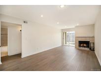 Bright living room with wood floors, fireplace and a sliding glass door to the outside at 865 S Quebec St # 103B, Denver, CO 80247